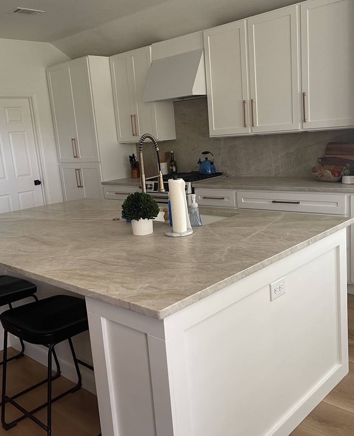 Quartzite kitchen countertops and island with matching backsplash in a white shaker kitchen