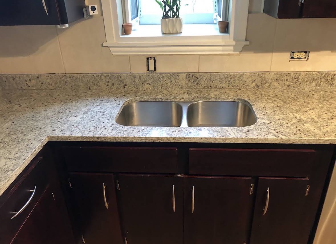 Granite countertop with undermount double-bowl stainless sink beneath a kitchen window
