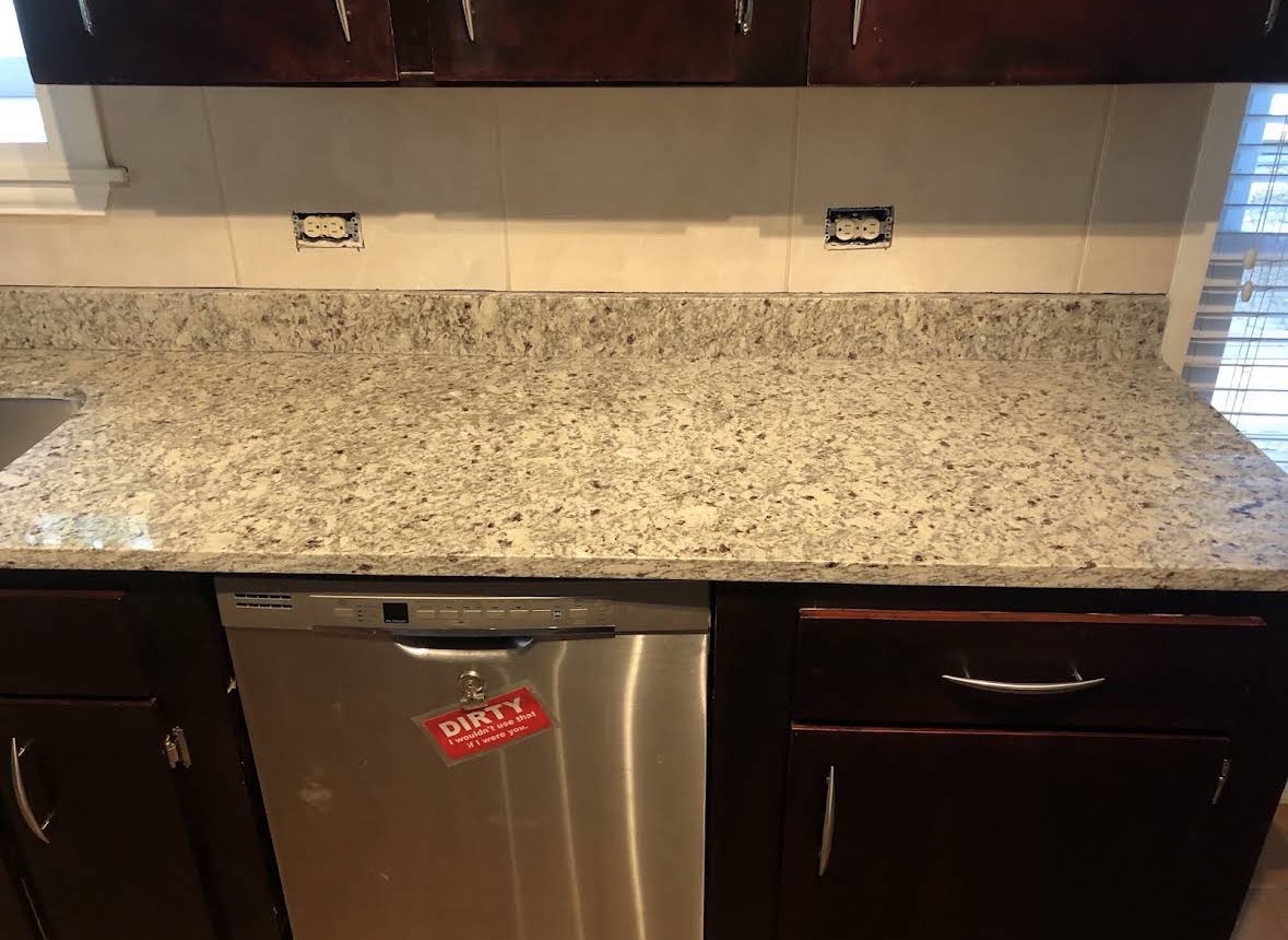 Granite countertop over dishwasher run fitted to existing wall tile