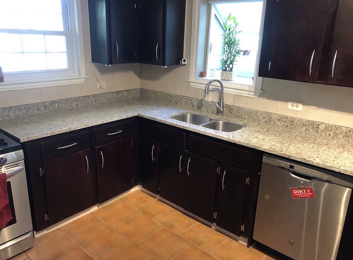 L-shaped speckled granite kitchen countertops with espresso cabinets and undermount sink