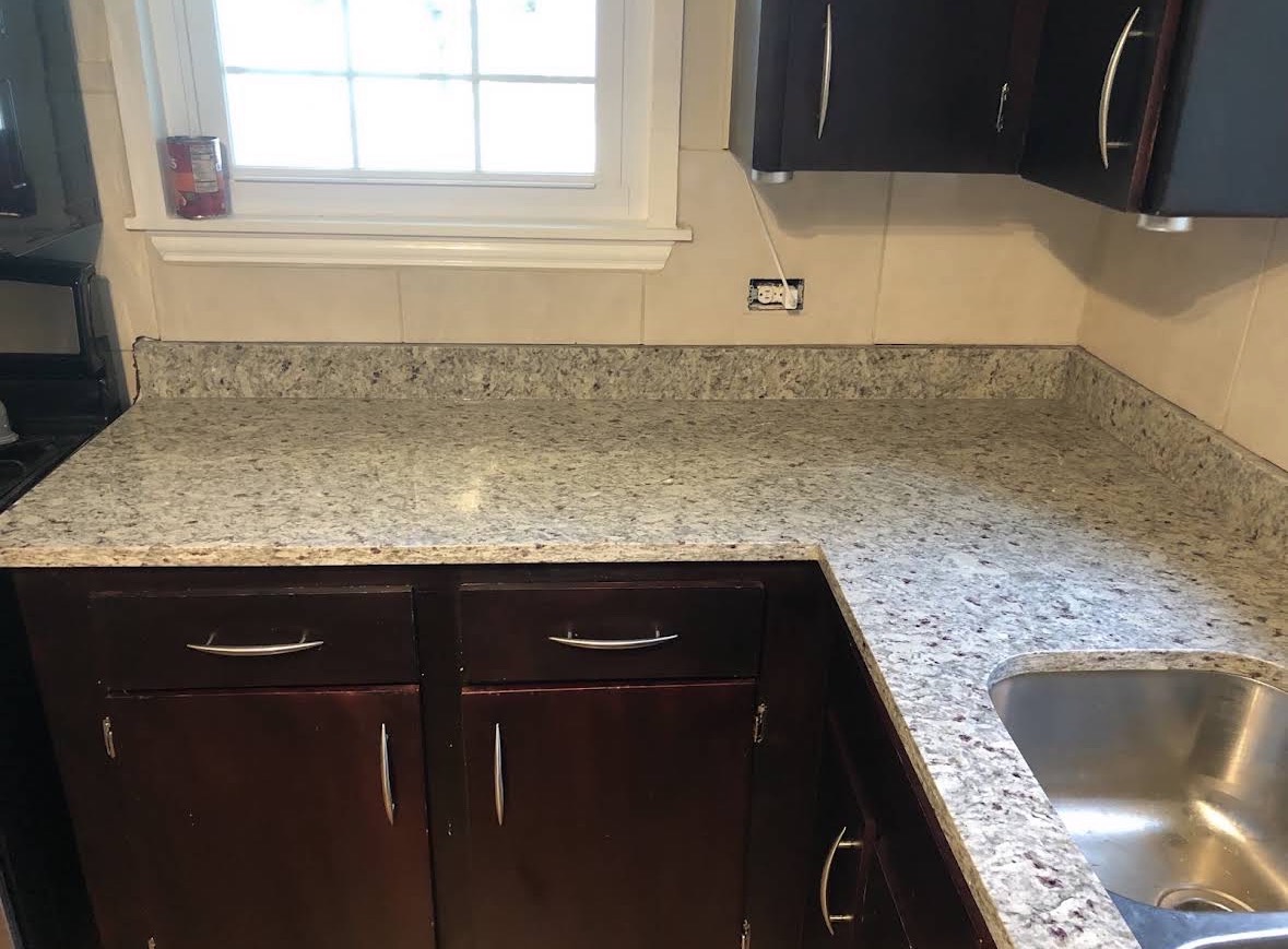 Granite counter run with 4-inch matching backsplash along a tiled wall